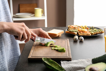 Woman preparing tasty sandwich with avocado in kitchen