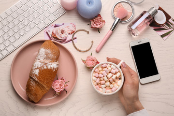 Young woman drinking cacao with marshmallows on white table