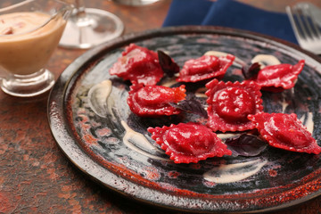 Plate with tasty ravioli on table