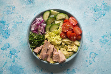 Avocado Tuna Salad in a plate on blue table. 