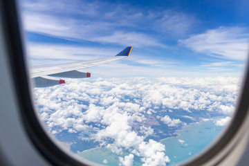 Naklejka na ściany i meble Airplane wing view out of the window the cloudy sky background, Travel and Holiday vacation concept