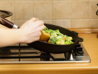 Woman cooking stir fry frozen vegetable on pan