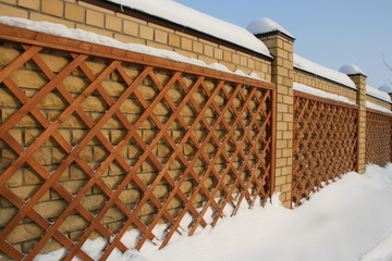 Wooden lattice on the background of a brick fence