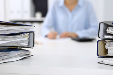 Binders with papers are waiting to be processed by business woman or bookkeeper back in blur....