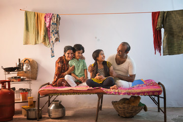 Middle Class Family sitting on camp bed at home	
