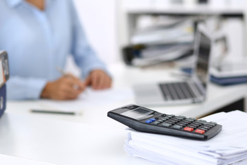 Calculator and binders with papers are waiting to be processed by business woman or bookkeeper back...