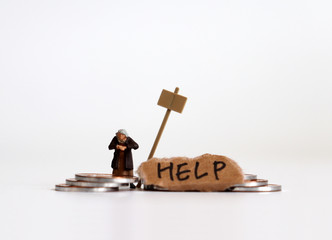 Miniature people and coins. A concept on economic hardship. A torn piece of paper with HELP written...