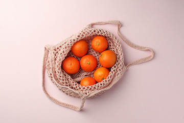 Zero waste, plastic free recycled textile produce bag for carrying fruit or vegetables on pink background. Recycle closeup, minimal concept