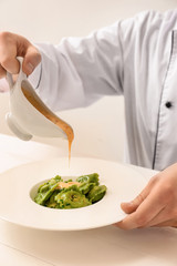 Male chef preparing for serving tasty ravioli on table