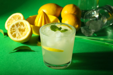 Glass of tasty cold lemonade on color background