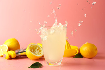 Fototapeta Glass of tasty cold lemonade with splashes on color background obraz