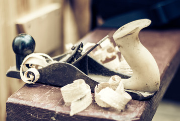 Joinery – old wooden plane and chips in a workshop of the carpenter, retro concept.