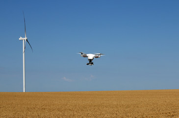 Fototapeta na wymiar drone flying over wheat field with wind turbine