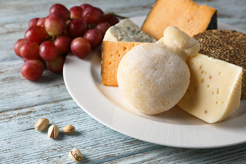 Plate with assortment of tasty cheese on wooden table