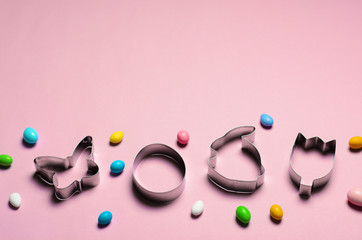 Fototapeta premium Easter Concept, Cookie Cutters and Chocolate Eggs on Pink Background
