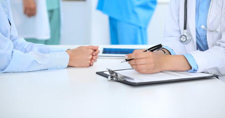 Doctor and patient discussing something, just hands at the table, white background