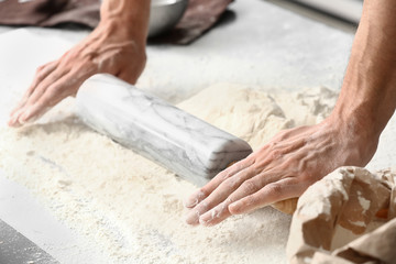 Obraz na płótnie Canvas Young man preparing dough for bread in kitchen, closeup