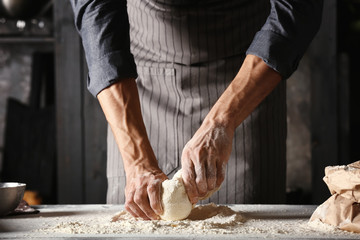 Young man preparing dough for bread in kitchen