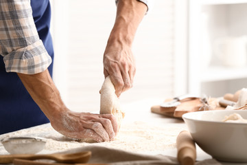 Young man preparing dough for bread in kitchen