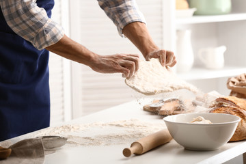 Young man preparing dough for bread in kitchen