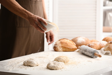 Young man preparing bread in kitchen