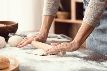 Young man preparing dough for bread in kitchen