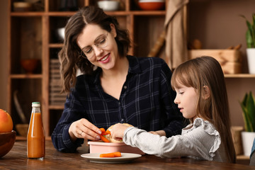 Mother with cute daughter preparing school lunch at home