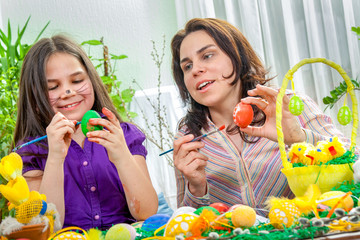 Mother and her children paint easter eggs