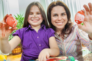 Mother and her children paint easter eggs