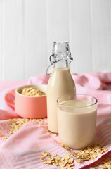 Glass and bottle of tasty oat milk on table