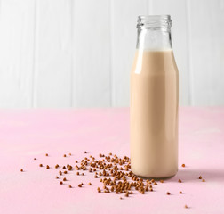 Bottle of tasty buckwheat milk on color table