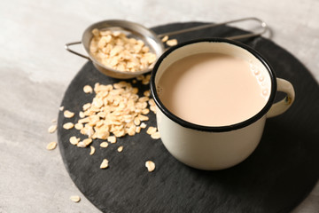 Mug of tasty oat milk on slate plate