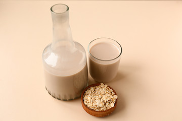 Bottle and glass of tasty oat milk on light background