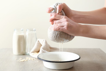 Woman preparing tasty oat milk on table