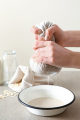 Woman preparing tasty oat milk on table