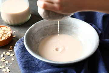 Woman preparing tasty oat milk on table, closeup