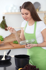 Obraz na płótnie Canvas Young happy woman cooking soup in the kitchen. Healthy meal, lifestyle and culinary concept. Smiling student girl preparing vegetarian meal at home