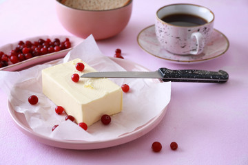 Plate with tasty butter and cranberries on color table