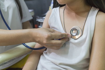 The Doctor examining asian girl and listen heartbeat with stethoscope in the hospital.