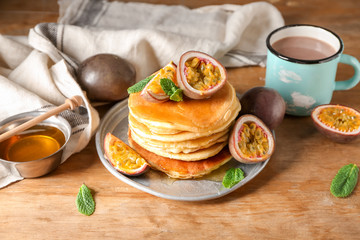 Tasty pancakes with passion fruit on wooden table