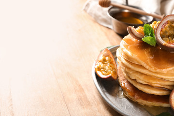 Tasty pancakes with passion fruit on wooden table