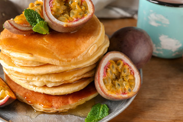 Tasty pancakes with passion fruit on table