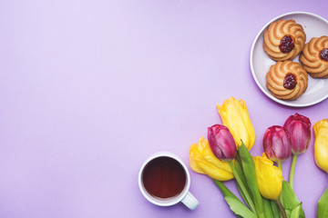 Bouquet of tulips and a Cup of coffee on a pink background. copy space. Flat lay, top view.
