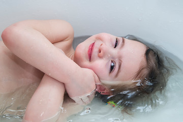 Baby girl smiling showing face just above water surface.