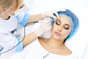Professional beautician doing eyebrow tattoo at woman face. Permanent brow makeup in beauty salon, closeup.  Cosmetology treatment