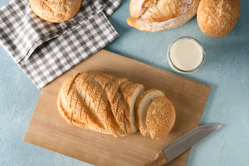 Tasty fresh bread with milk on color table