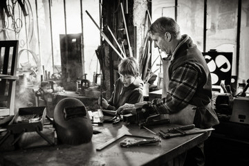A craftsman in his workshop teaches his work to his young son