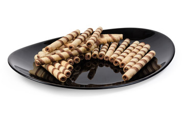Striped wafer tubes with chocolate cream on the black dish