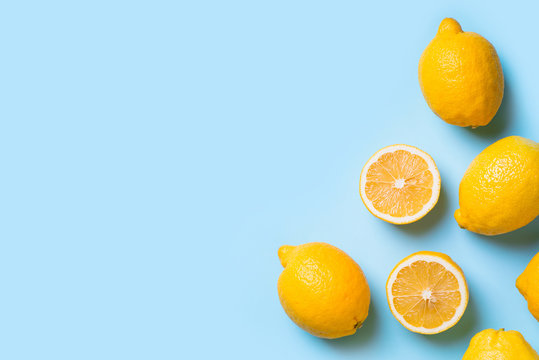 Ripe lemons flat lay with leaves on blue background