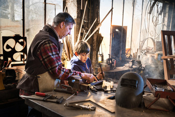 A craftsman in his workshop teaches his work to his young son